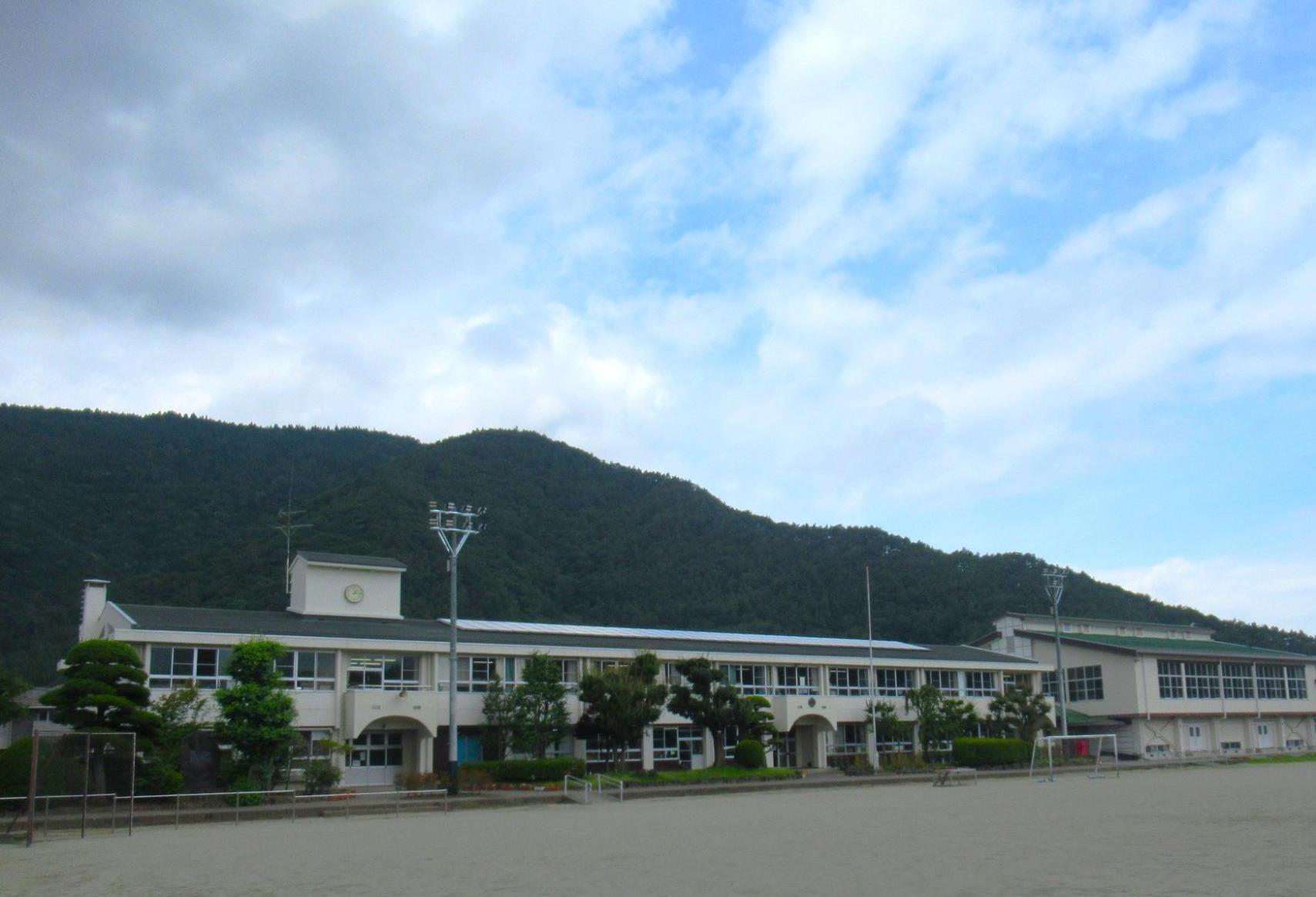 2階建ての白い校舎とグラウンドが写っている鳴沢村立鳴沢小学校の写真